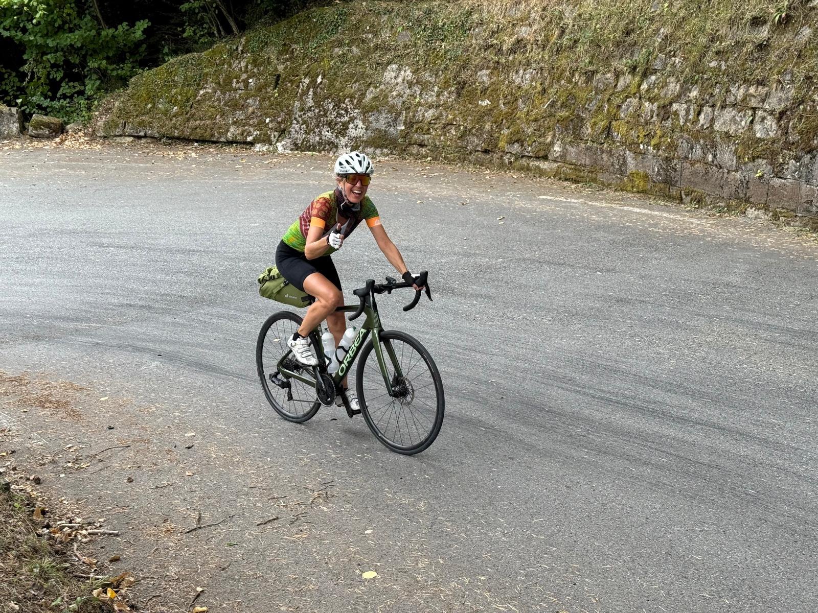 Isabelle Ledergerber beim Radfahren an einer bemoosten Steinmauer vorbei